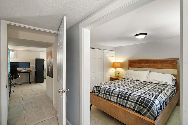 bedroom with light tile patterned floors, a textured ceiling, and a closet