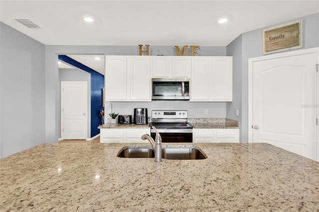 11207 Amber Ridge Dr, Zellwood, FL 32798 - kitchen featuring a sink, light stone countertops, stainless steel appliances, visible vents, and white cabinets