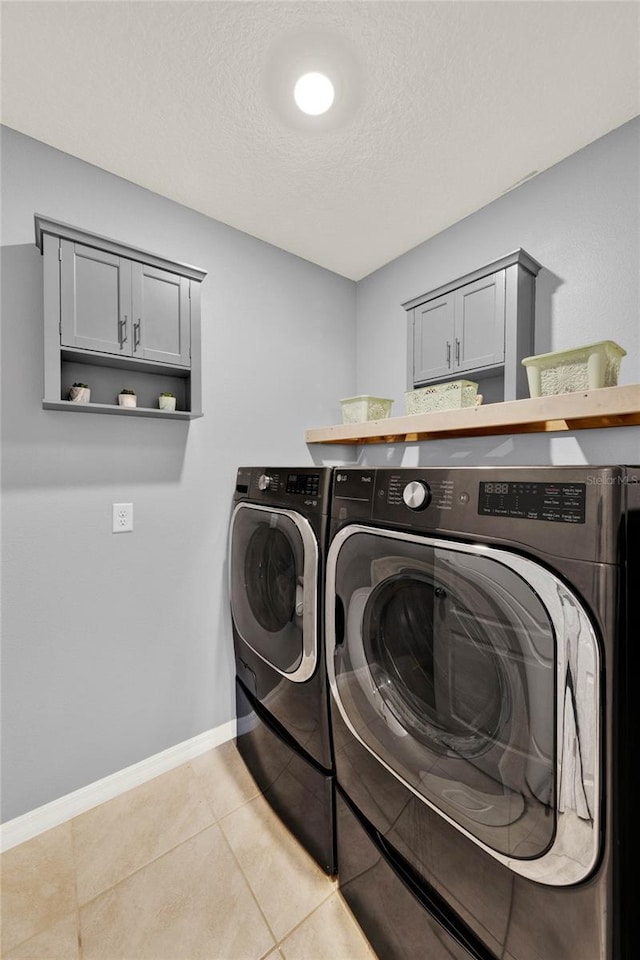 11207 Amber Ridge Dr, Zellwood, FL 32798 - laundry room with washing machine and dryer, a textured ceiling, light tile patterned floors, baseboards, and cabinet space