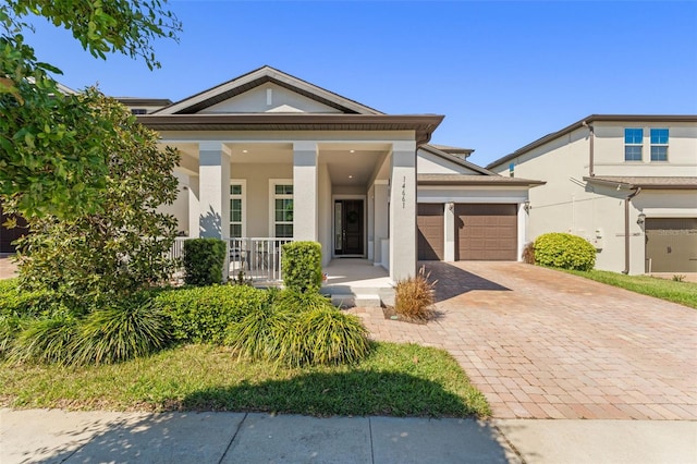 view of front of home with covered porch, stucco siding, driveway, and a garage