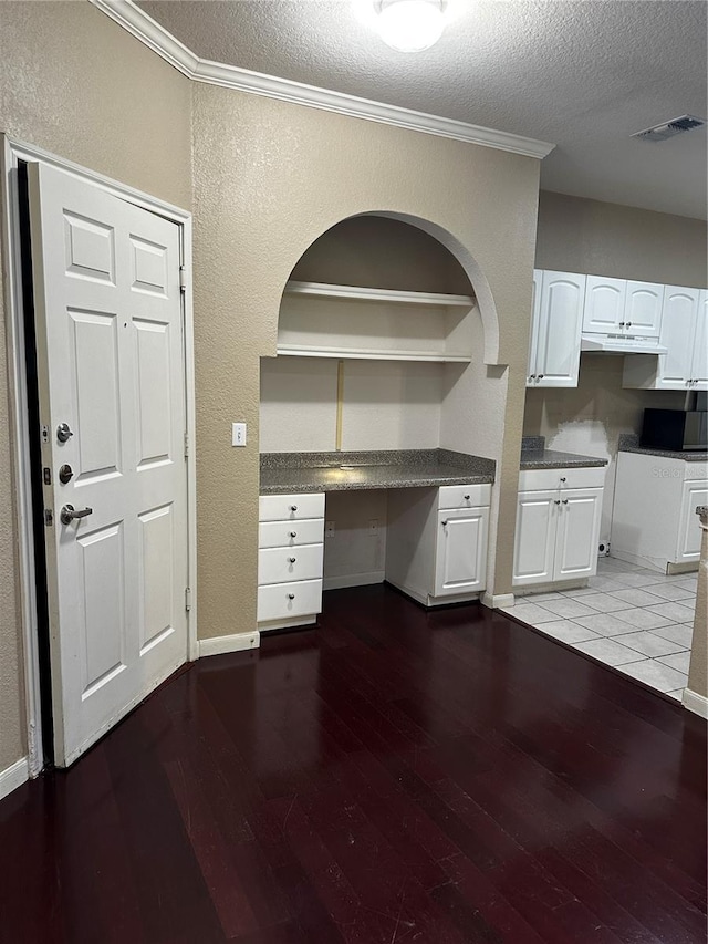 860 N Orange Ave Unit 149, Orlando, FL 32801 - kitchen featuring hardwood / wood-style floors, built in study area, a textured ceiling, under cabinet range hood, and white cabinets