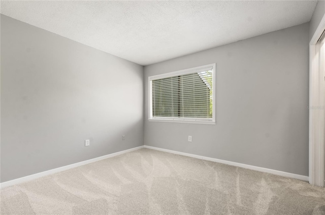 unfurnished room featuring baseboards, a textured ceiling, and carpet