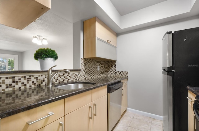 kitchen with light tile patterned flooring, dark stone counters, a sink, backsplash, and stainless steel appliances