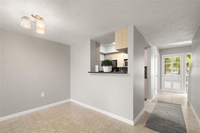 interior space with baseboards, a textured ceiling, and light tile patterned floors