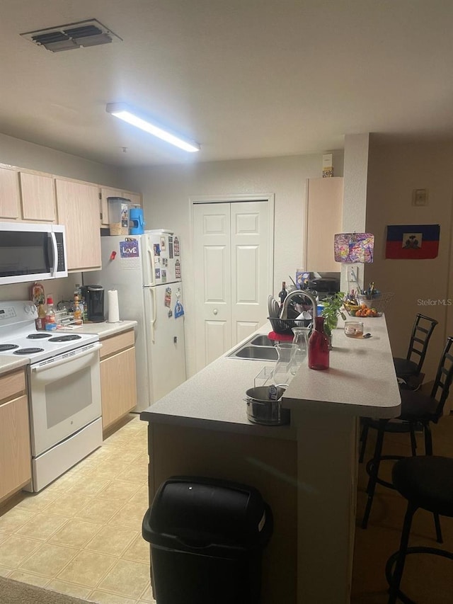 5471 Vineland Rd Unit 7108, Orlando, FL 32811 - kitchen featuring a sink, a breakfast bar, light brown cabinetry, white appliances, and visible vents