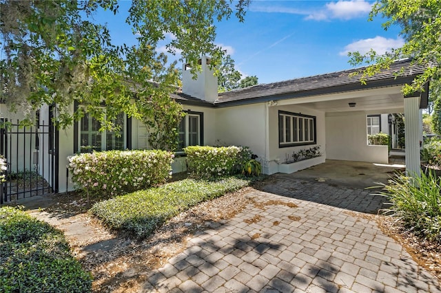 1701 Palmer Ave, Winter Park, FL 32789 - rear view of house featuring a carport, stucco siding, a chimney, and fence