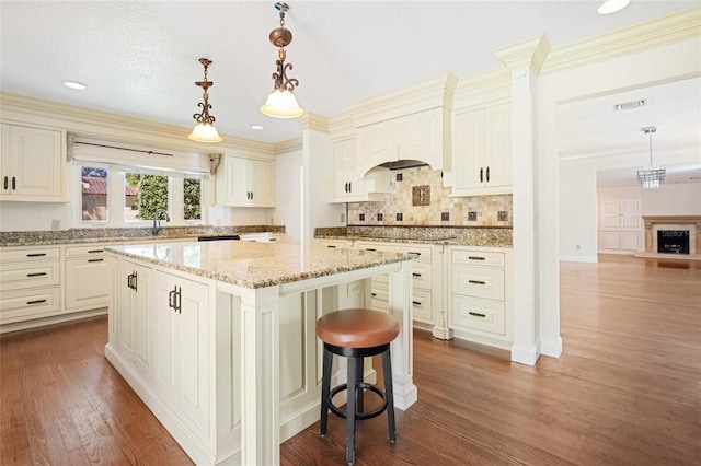 1701 Palmer Ave, Winter Park, FL 32789 - kitchen with visible vents, a kitchen island, a breakfast bar area, light stone countertops, and dark wood-style flooring