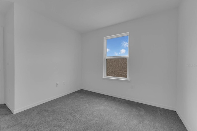 unfurnished room featuring baseboards and dark colored carpet