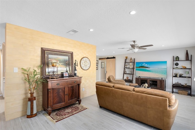 living room featuring visible vents, a ceiling fan, recessed lighting, a barn door, and light wood finished floors