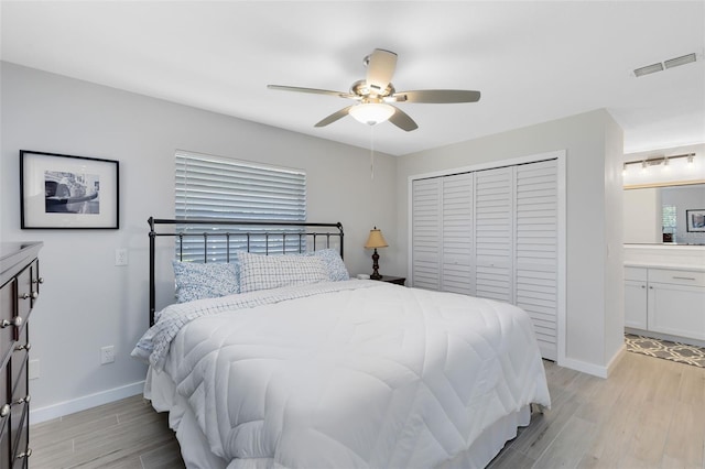 bedroom with light wood-type flooring, visible vents, baseboards, and a closet