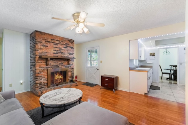 4366 Roanne Dr, Orlando, FL 32817 - living room featuring a textured ceiling, light wood-style flooring, a fireplace, and ceiling fan
