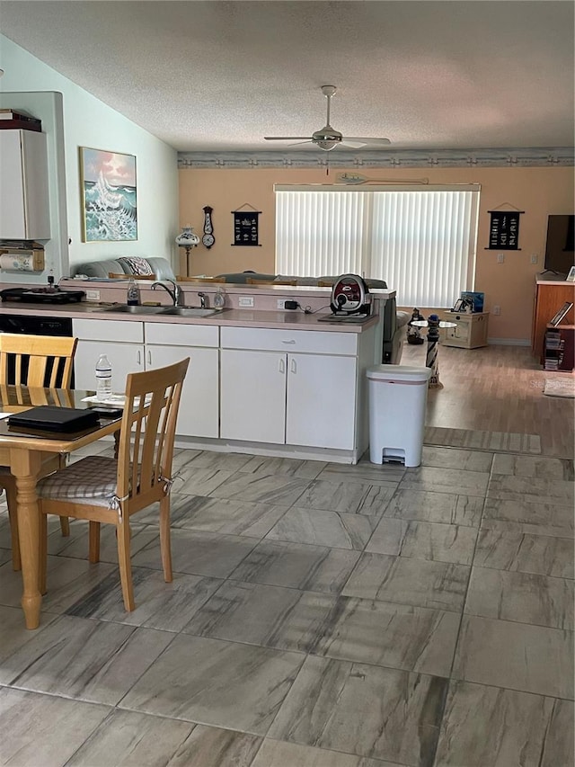 kitchen featuring a sink, a textured ceiling, white cabinetry, ceiling fan, and marble finish floor