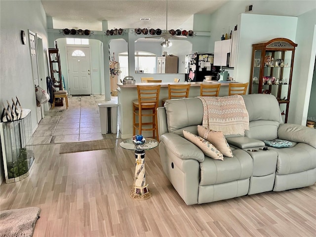 living room featuring arched walkways, visible vents, and light wood-style floors