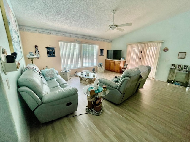 living room with a healthy amount of sunlight, ceiling fan, a textured ceiling, and vaulted ceiling