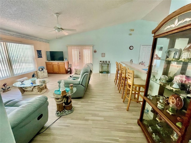 living room with light wood-style flooring, ceiling fan, and vaulted ceiling