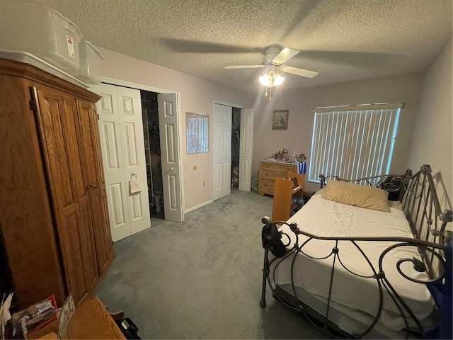 bedroom featuring carpet flooring, a textured ceiling, a ceiling fan, and multiple closets