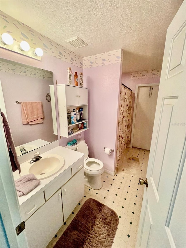 full bath featuring toilet, vanity, a textured ceiling, visible vents, and tile patterned floors