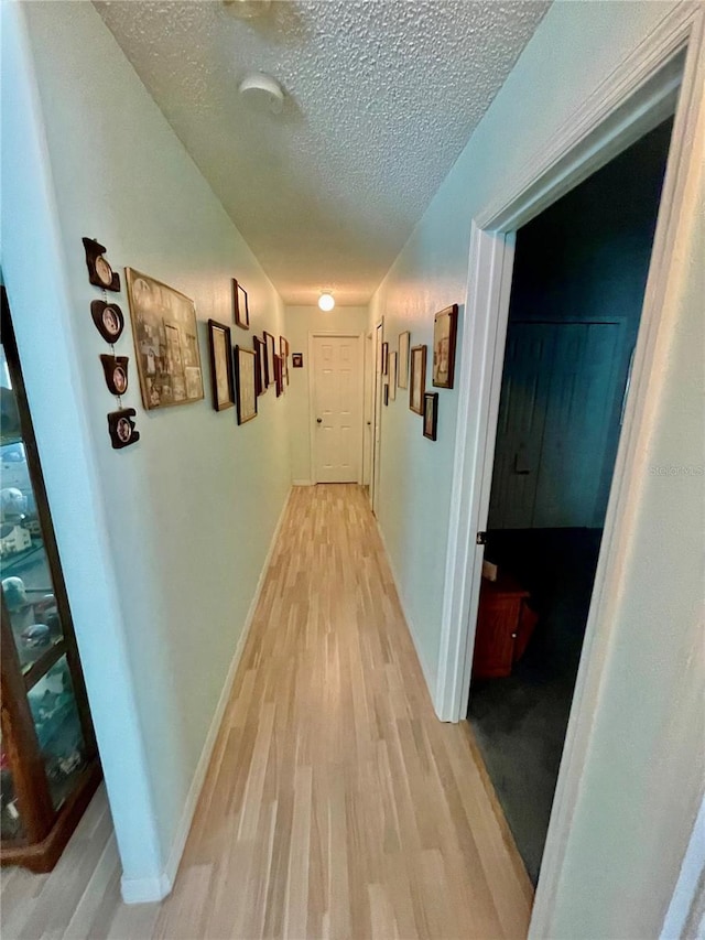 hall with light wood-style flooring and a textured ceiling