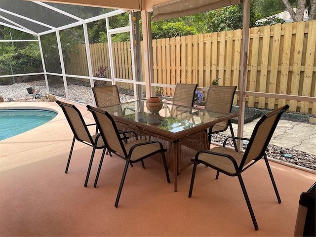 view of patio with a fenced backyard, a fenced in pool, outdoor dining space, and glass enclosure