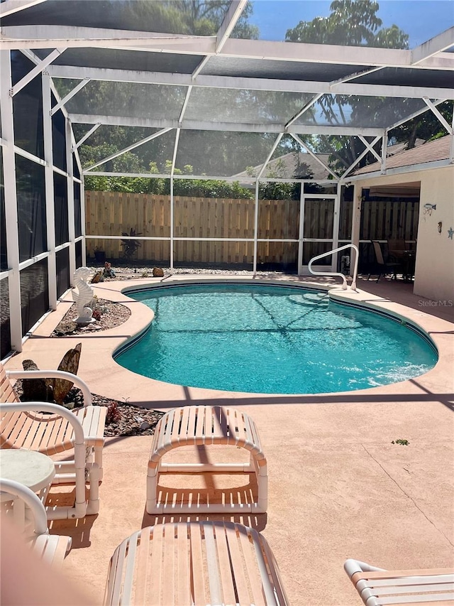 view of swimming pool featuring a patio area, fence, and glass enclosure
