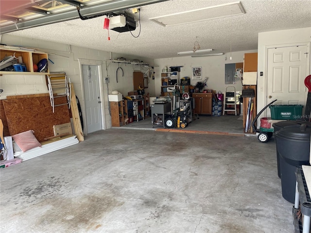 garage with electric panel, concrete block wall, and a garage door opener