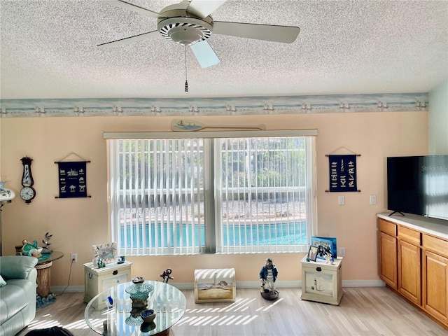 6037 Hickory Grove Ln, Port Orange, FL 32128 - living room featuring a textured ceiling, ceiling fan, light wood-style flooring, and baseboards