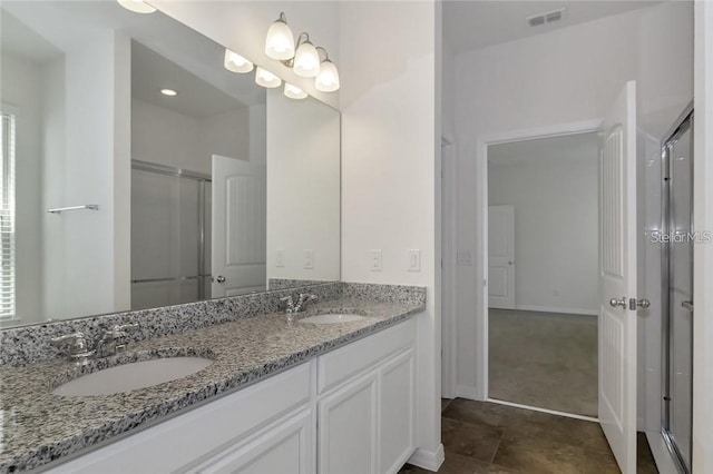 full bathroom with double vanity, a shower stall, visible vents, and a sink