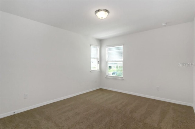 spare room featuring baseboards and carpet