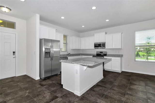 kitchen featuring baseboards, a wealth of natural light, stainless steel appliances, and a kitchen island