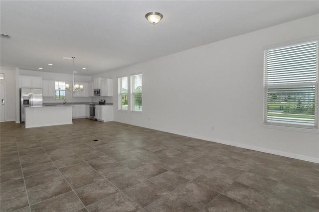 unfurnished living room with baseboards, a notable chandelier, visible vents, and recessed lighting