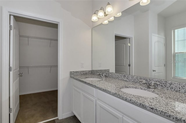 full bathroom with a spacious closet, a sink, and double vanity