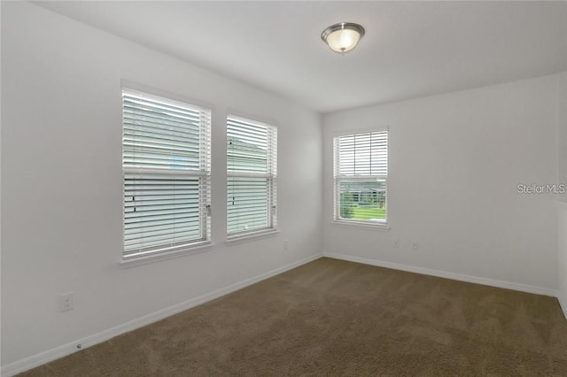 carpeted empty room featuring baseboards