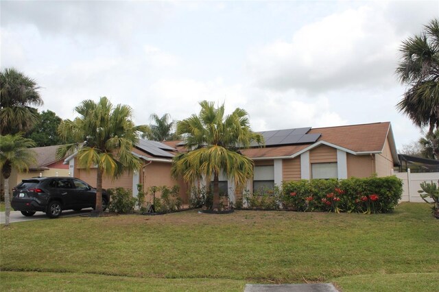855 San Pedro Ct, Kissimmee, FL 34758 - ranch-style house featuring solar panels, driveway, fence, and a front lawn