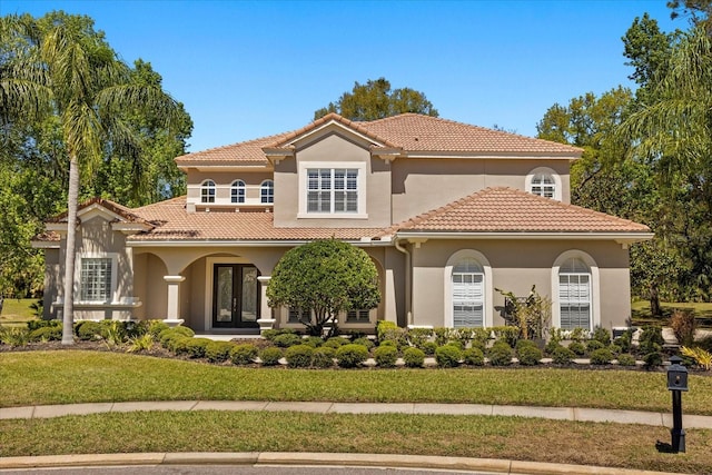mediterranean / spanish home featuring french doors, a front yard, stucco siding, and a tiled roof