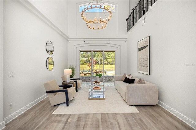 living area with baseboards, wood finished floors, and a chandelier