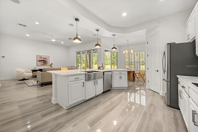 kitchen with visible vents, open floor plan, appliances with stainless steel finishes, white cabinets, and a sink