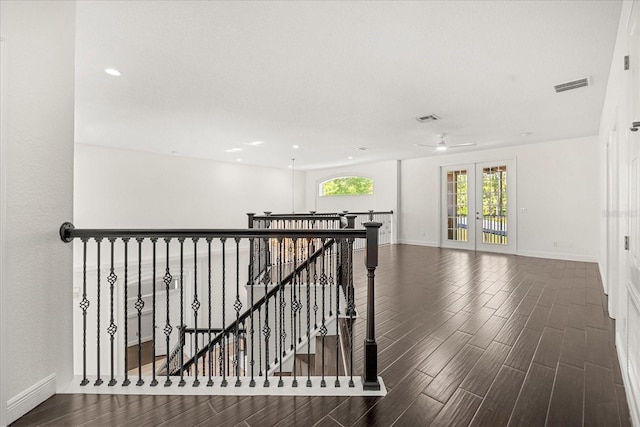 hallway featuring an upstairs landing, visible vents, baseboards, and wood finished floors