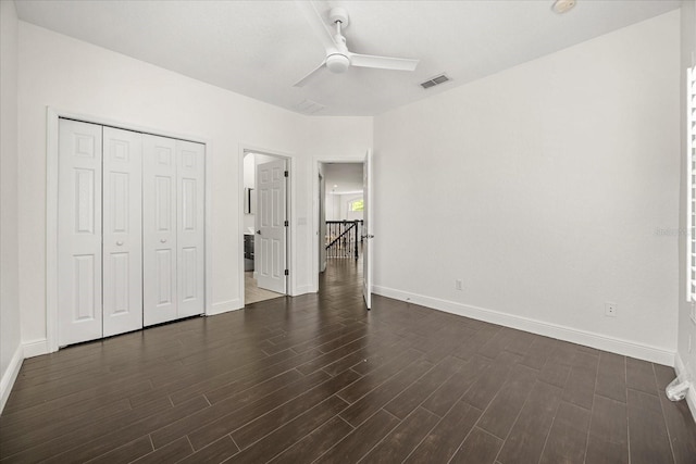 unfurnished bedroom featuring baseboards, visible vents, ceiling fan, dark wood-type flooring, and a closet