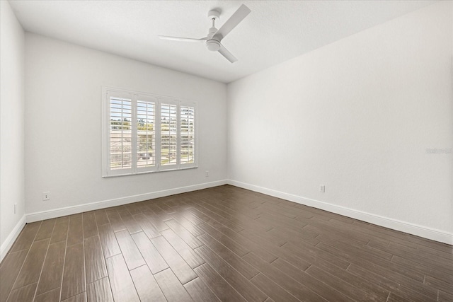 empty room with baseboards, dark wood finished floors, and a ceiling fan