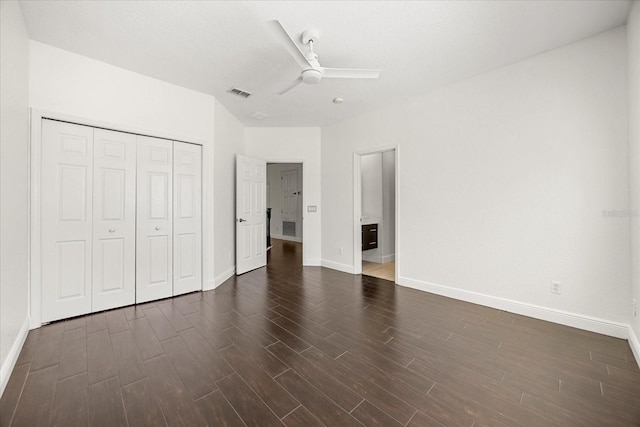 unfurnished bedroom featuring dark wood-type flooring, baseboards, visible vents, and a closet