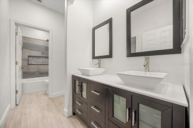 bathroom with double vanity, toilet, baseboards, and a sink