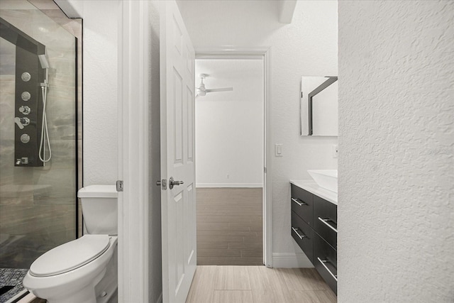 bathroom with vanity, wood tiled floor, a shower stall, toilet, and a textured wall