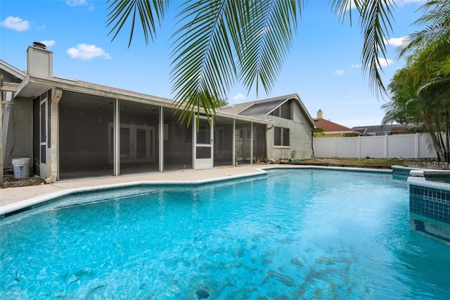 view of pool featuring a sunroom, fence, and a pool with connected hot tub