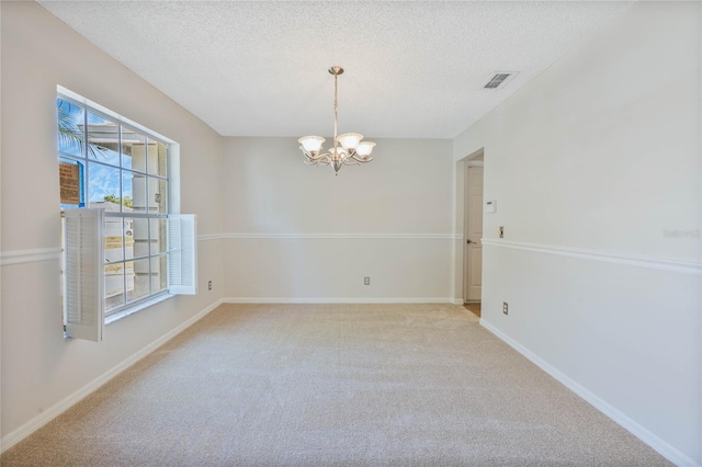 empty room with visible vents, a textured ceiling, a chandelier, and light carpet