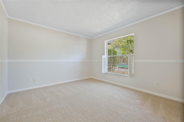 carpeted spare room featuring a textured ceiling, ornamental molding, and baseboards