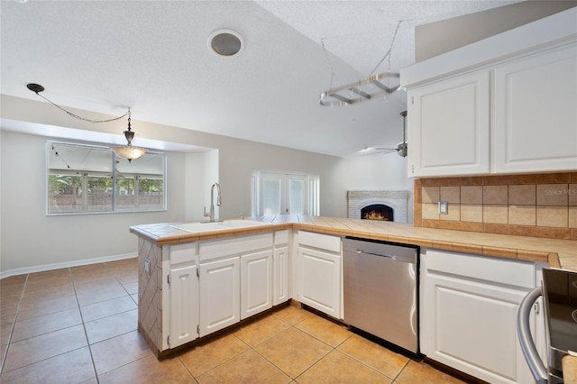 kitchen with ceiling fan, a sink, dishwasher, a brick fireplace, and light tile patterned floors