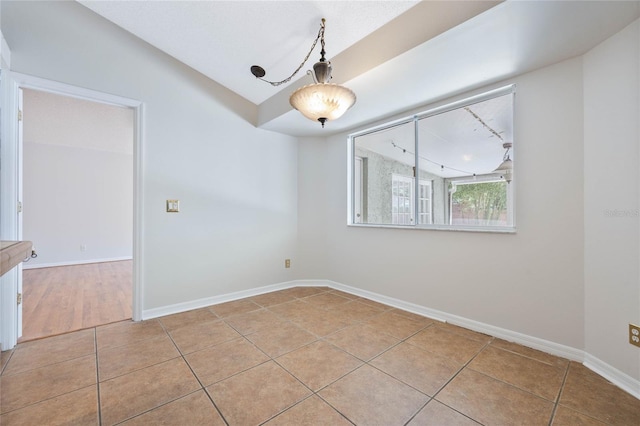 spare room with baseboards and light tile patterned floors