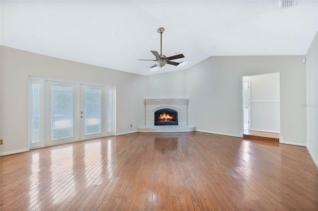unfurnished living room featuring light wood finished floors, a brick fireplace, a ceiling fan, baseboards, and vaulted ceiling