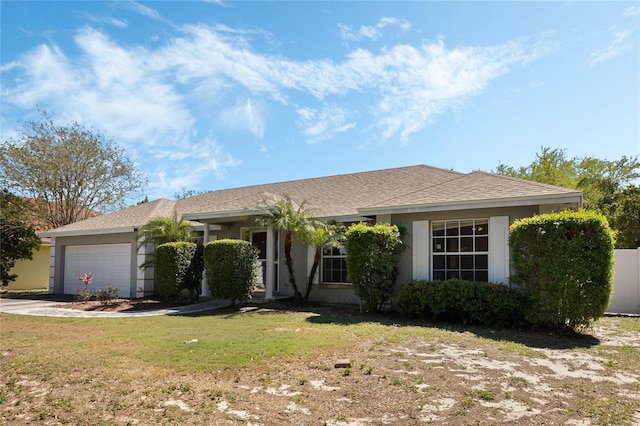 ranch-style home featuring an attached garage, stucco siding, a front yard, and concrete driveway
