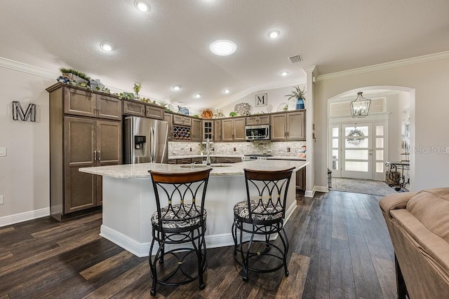 5729 Hickey Way, The Villages, FL 32163 - kitchen featuring lofted ceiling, stainless steel appliances, decorative backsplash, a sink, and arched walkways